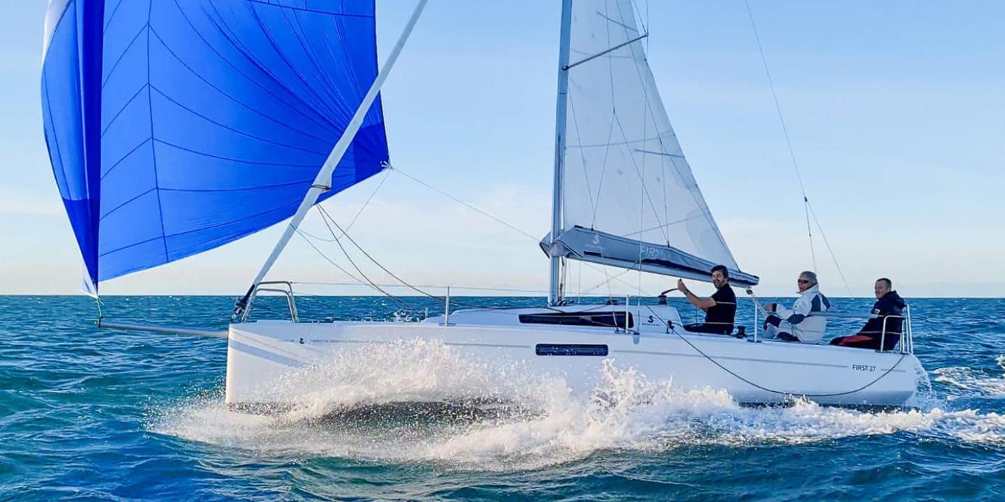 Beneteau First 27 sailboat sailing on the water with a clear blue sky