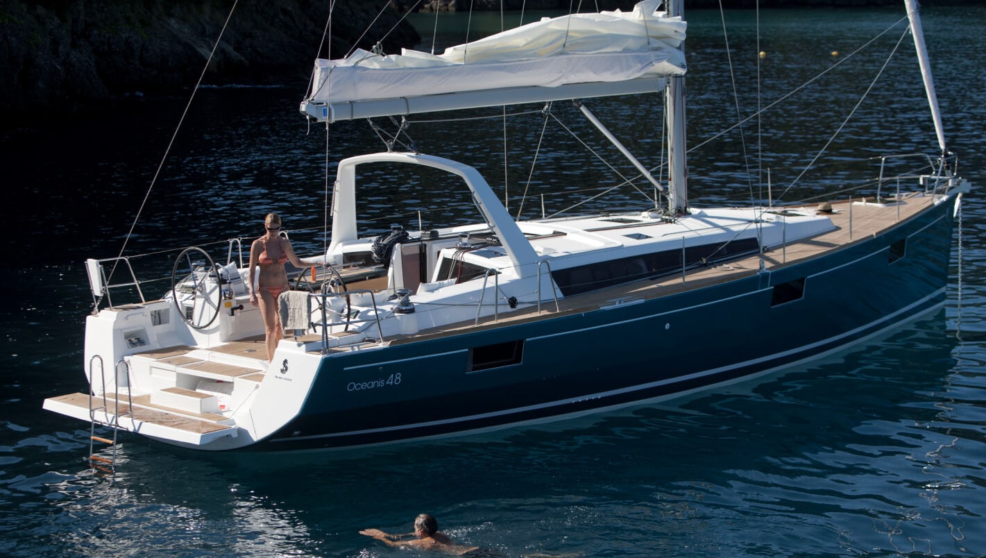 Beneteau Oceanis 48 yacht sailing on the lake with mountains in the background