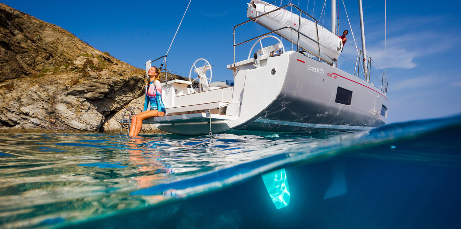 Yacht Beneteau naviguant devant une chaîne de montagnes